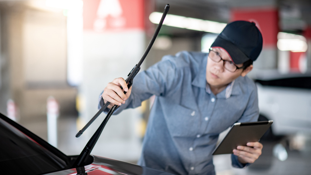 Asian auto mechanic checking windshield wiper